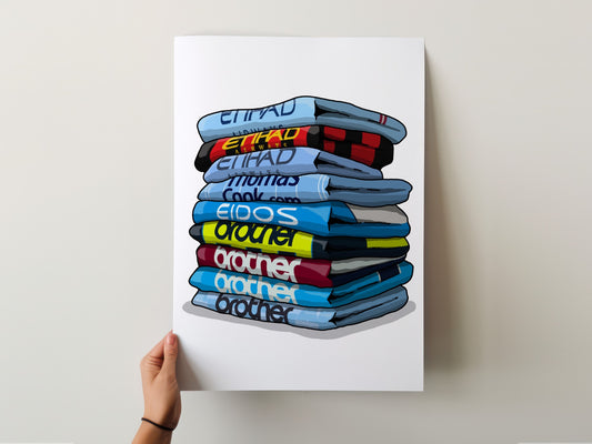 A hand is holding up a poster with a stack of colorful t-shirts on it.