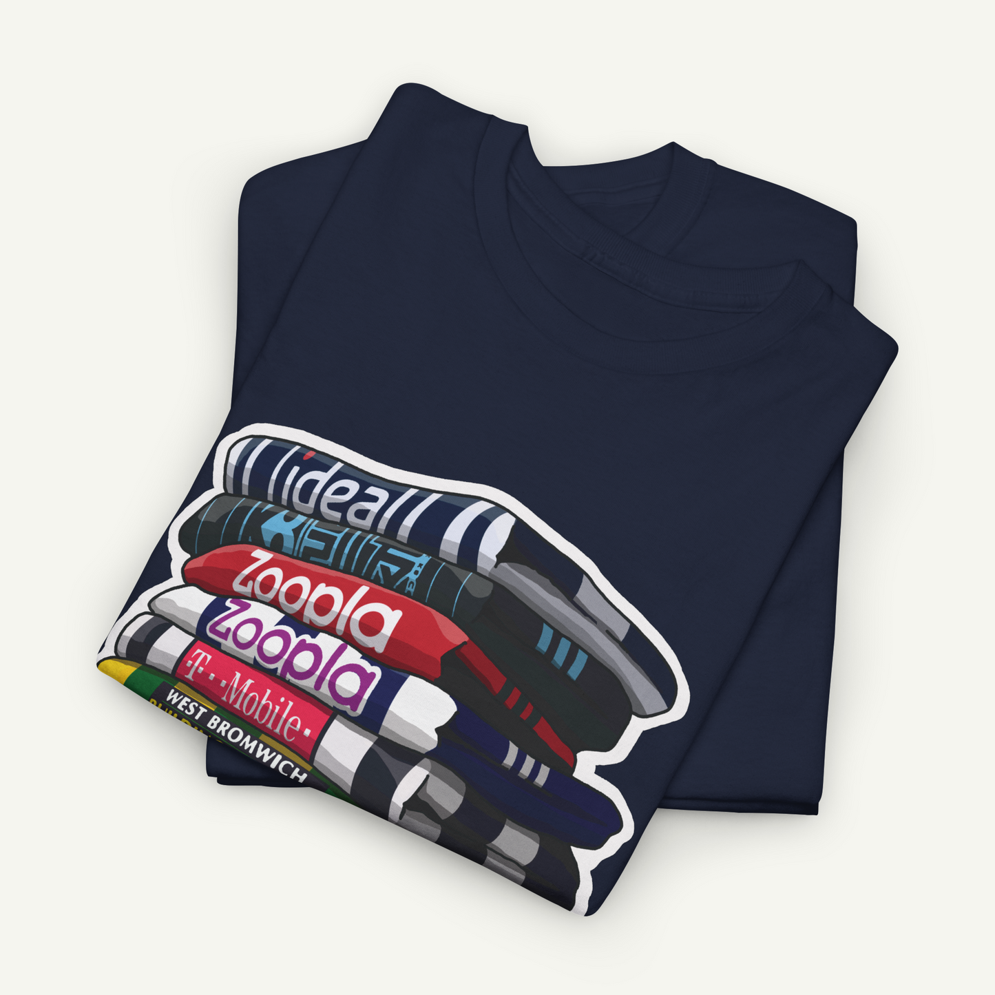 A navy blue t-shirt with a graphic design depicting a stack of books with the text "ideal", "zooala", "zooala", "T-Mobile", and "West Bromwich" printed on it.