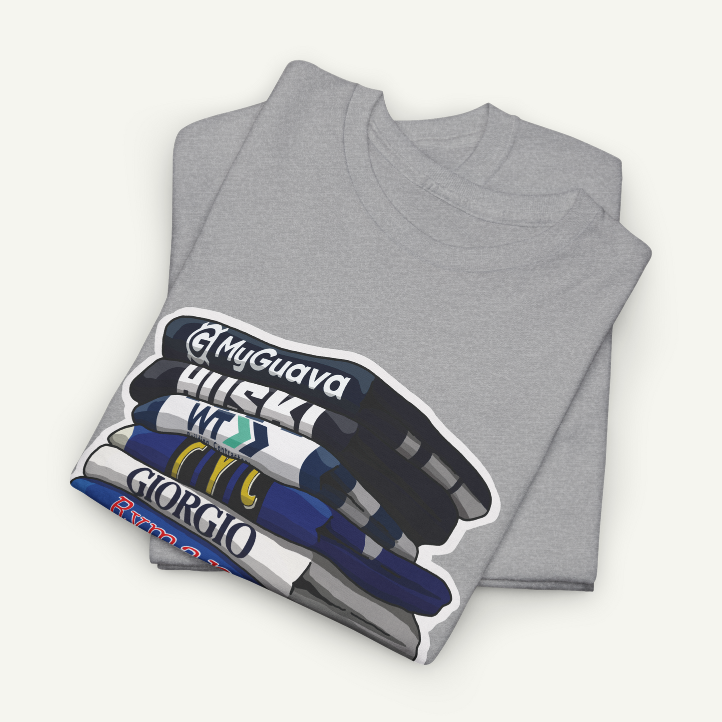 A gray t-shirt with a graphic design depicting a stack of books or magazines with various titles written on them.