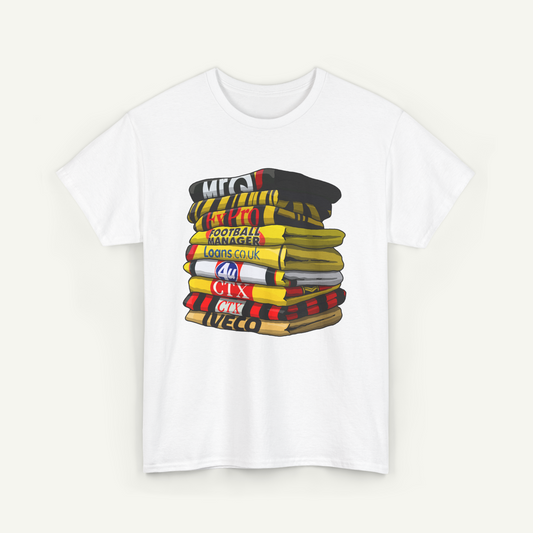 A white t-shirt with a graphic design depicting a stack of colorful towels or blankets with various text printed on them.