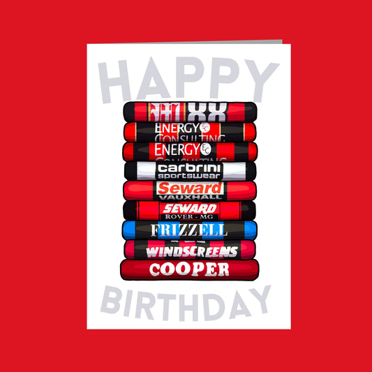 A birthday card with a stack of various sports equipment, including a red and black skateboard, a red and black bicycle, and a red and black snowboard. The text "Happy Birthday" is displayed in the center of the image.