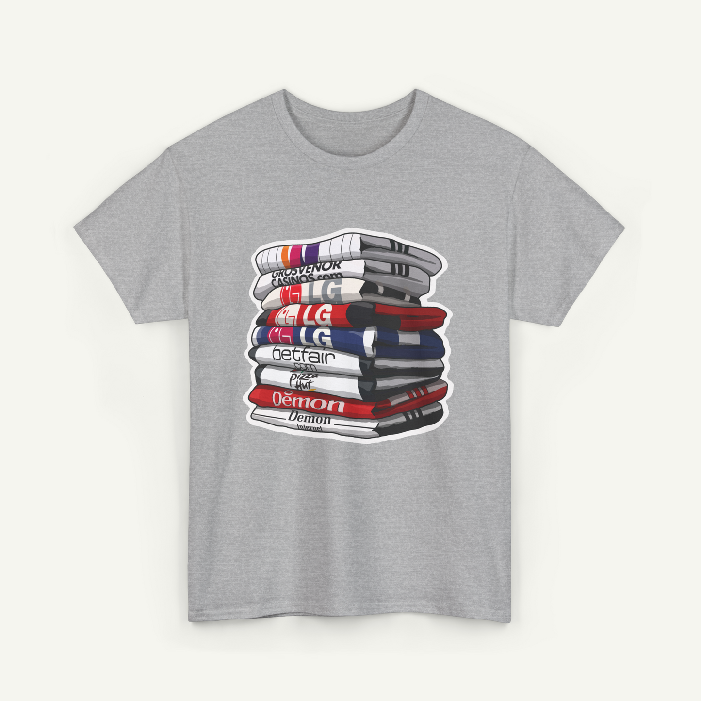 A gray t-shirt with a graphic design depicting a stack of books or magazines with various text and logos on the covers.