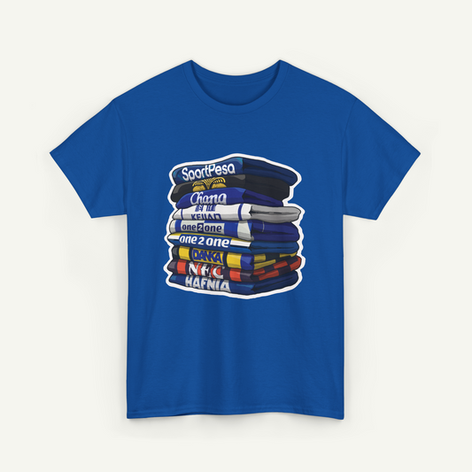 A blue t-shirt with a graphic design depicting a stack of books or magazines with various titles written on them.