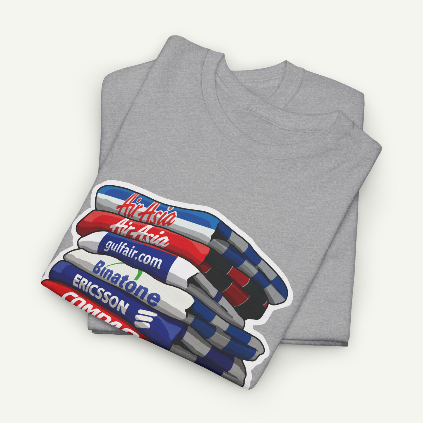 A gray t-shirt with a graphic design depicting a stack of books or magazines with various text elements on the covers.