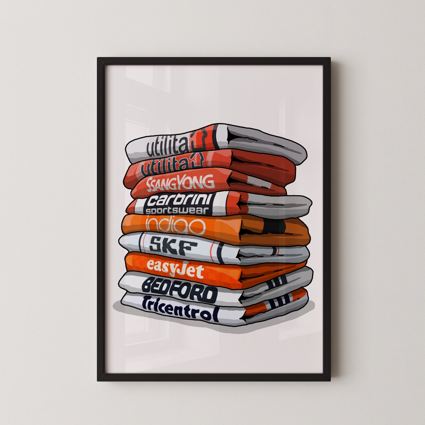 A framed illustration of a stack of colorful towels with various text printed on them, including "utilitat", "Sangyong", "CARBINI", "indio", "SKF", "easyJet", "BEDFORD", and "tricentro".