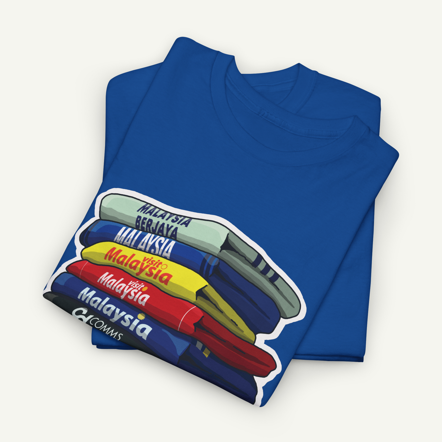 A blue t-shirt with a graphic design depicting a stack of books or magazines with the text "Malaysia" printed on them.