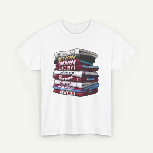 A white t-shirt with a graphic design depicting a stack of books or magazines with various text on the covers.