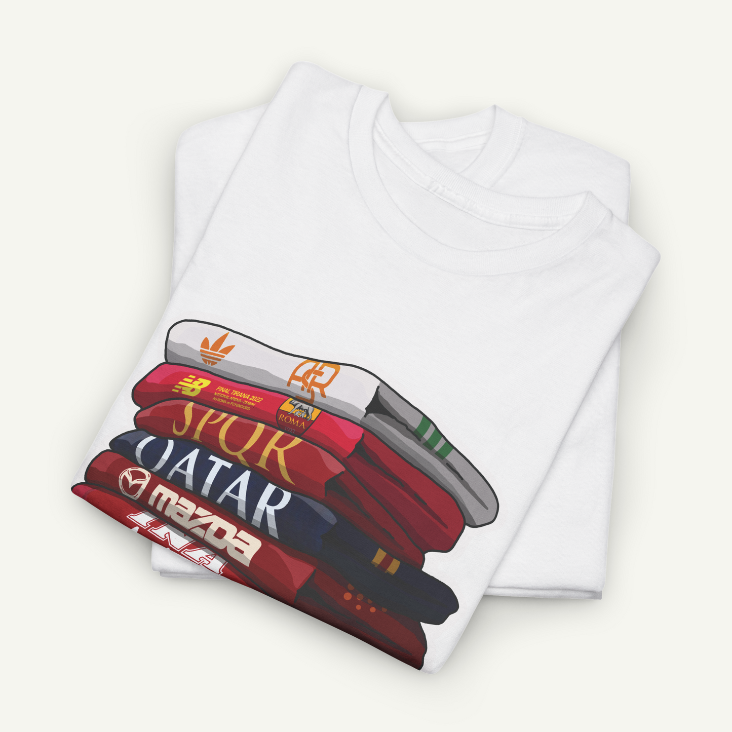 A white t-shirt with a graphic design depicting a stack of books or magazines with the titles "SPUR", "QATAR", and "MAZDA" printed on them.