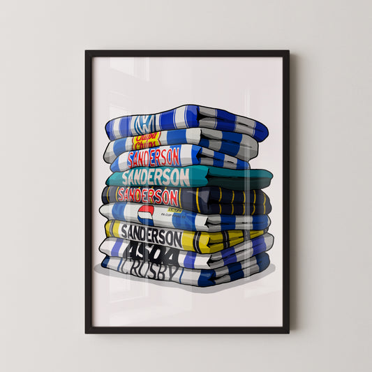 A framed illustration of a stack of rugby towels with various team names and logos printed on them.