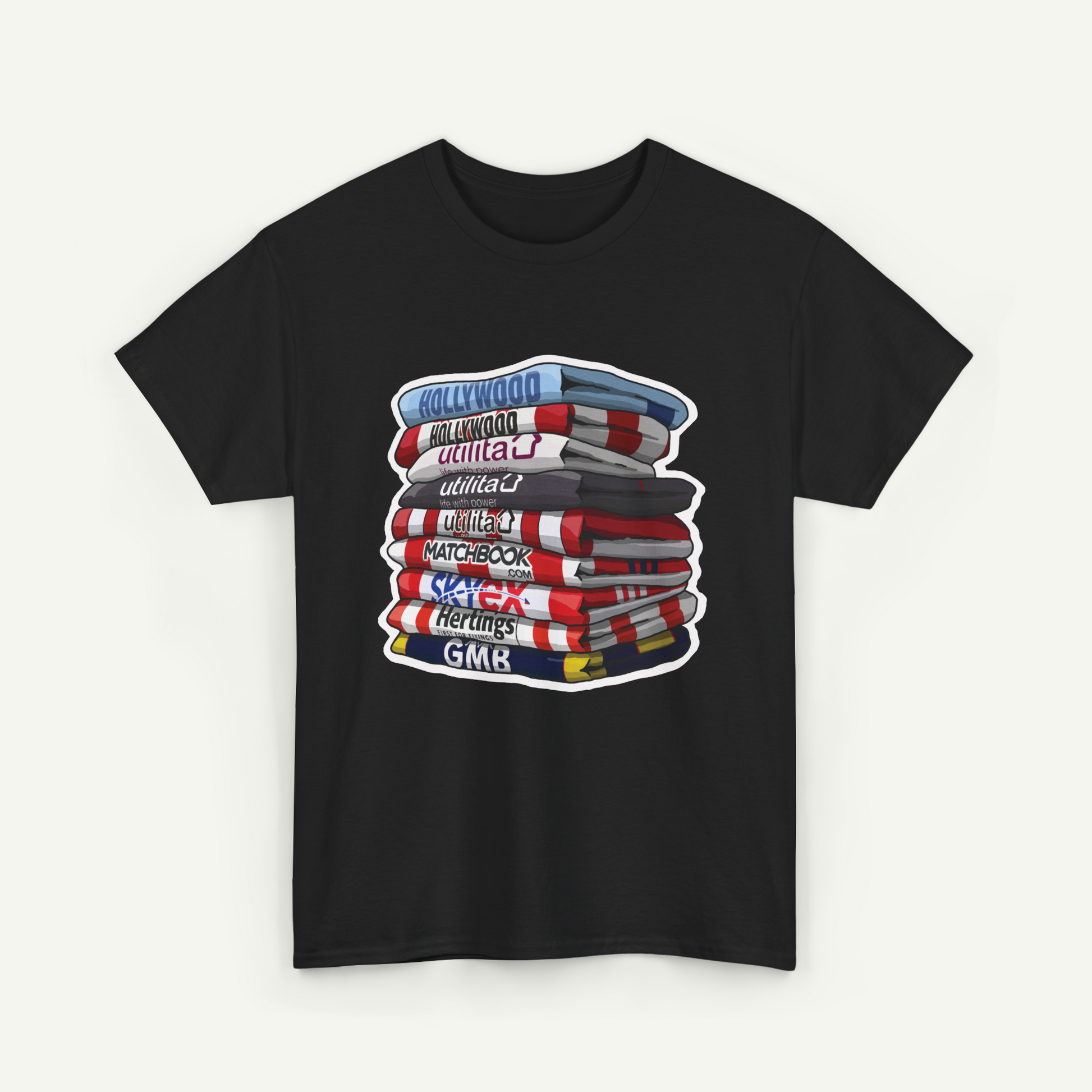 A black t-shirt with a graphic design depicting a stack of colorful books or magazines with various titles such as "Hollywood", "Utilities", "Matchbook", "Heritage", and "GMK".
