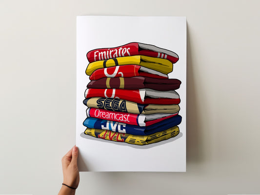 A hand is holding a poster with a stack of colorful, patterned shirts on it.