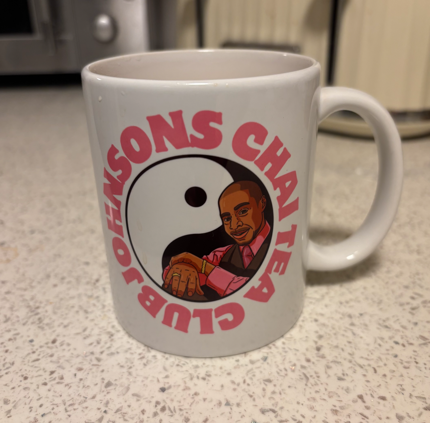 A white ceramic mug with a graphic design featuring a man in a pink shirt and a yin and yang symbol.