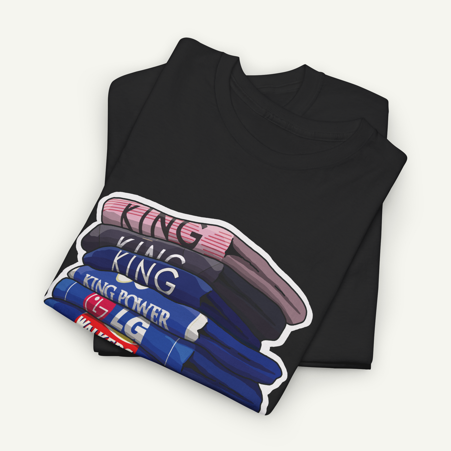 A black t-shirt with a graphic design depicting a stack of colorful shirts, with the word "KING" written on each shirt.
