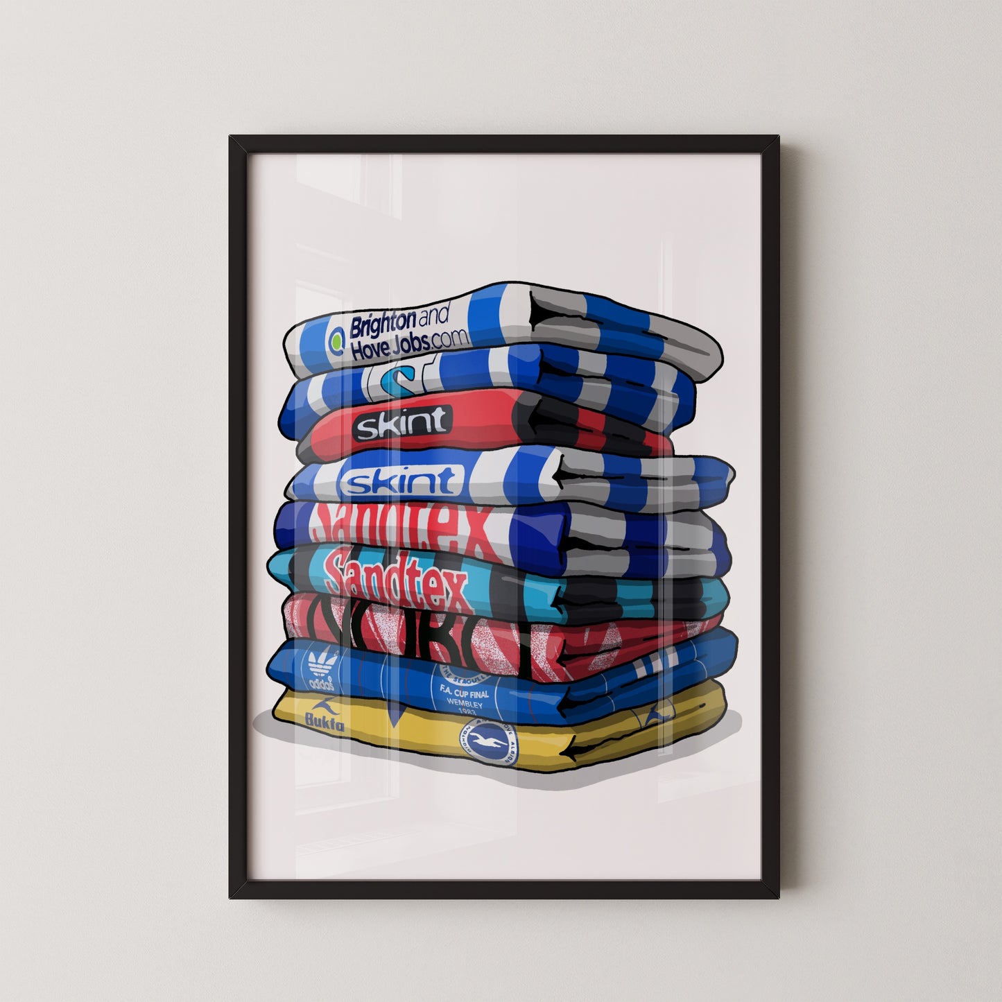 A framed illustration of a stack of colorful towels with various logos and text on them.