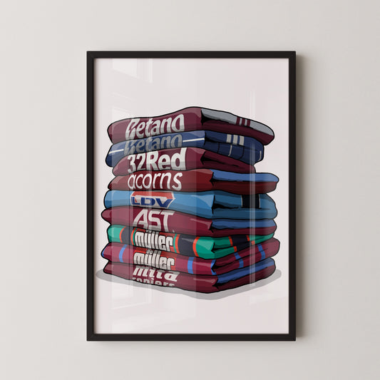A framed illustration of a stack of colorful t-shirts with various text and logos on them.