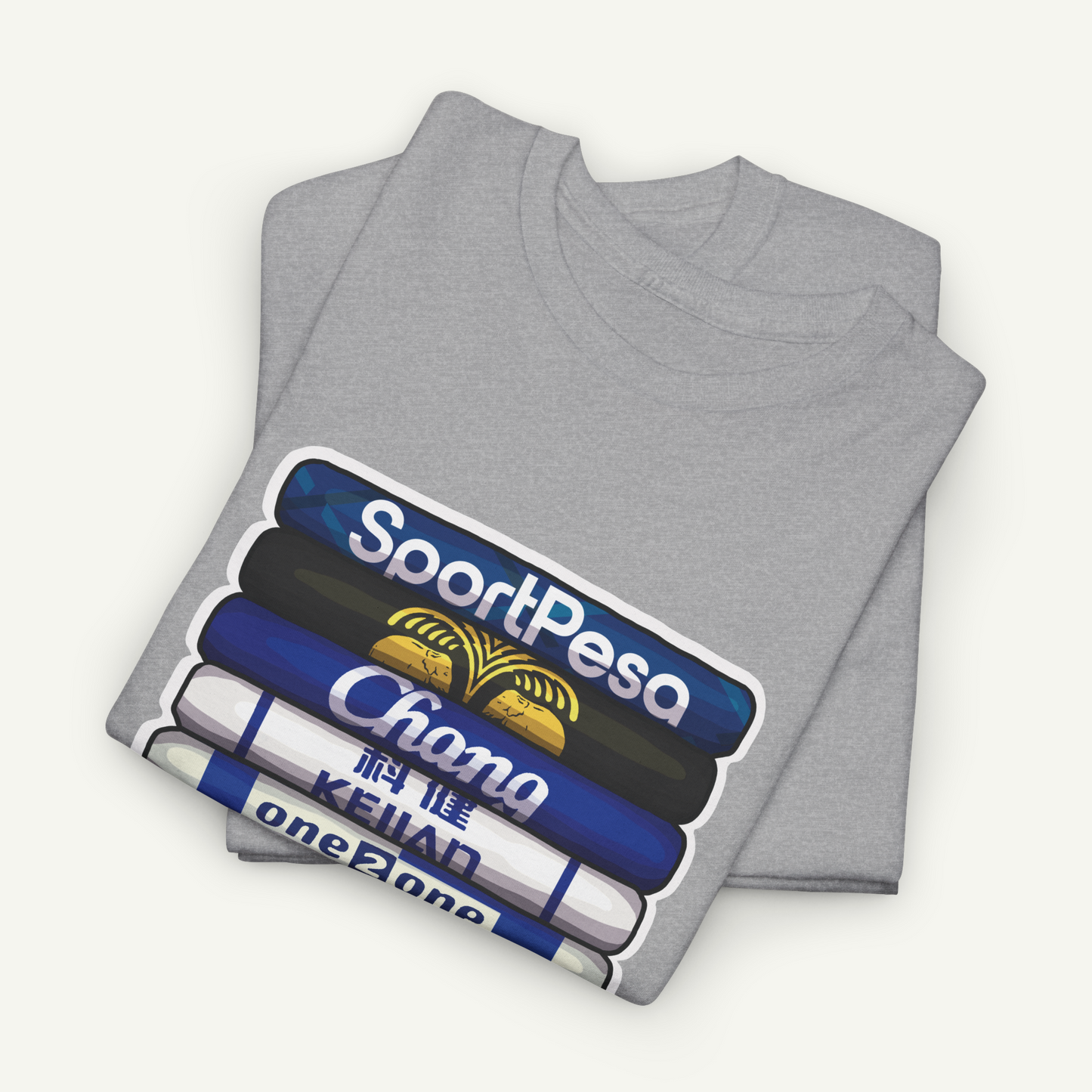 A gray t-shirt with a graphic design depicting a stack of books with the text "SportPesa Chana Keiyan" printed on them.
