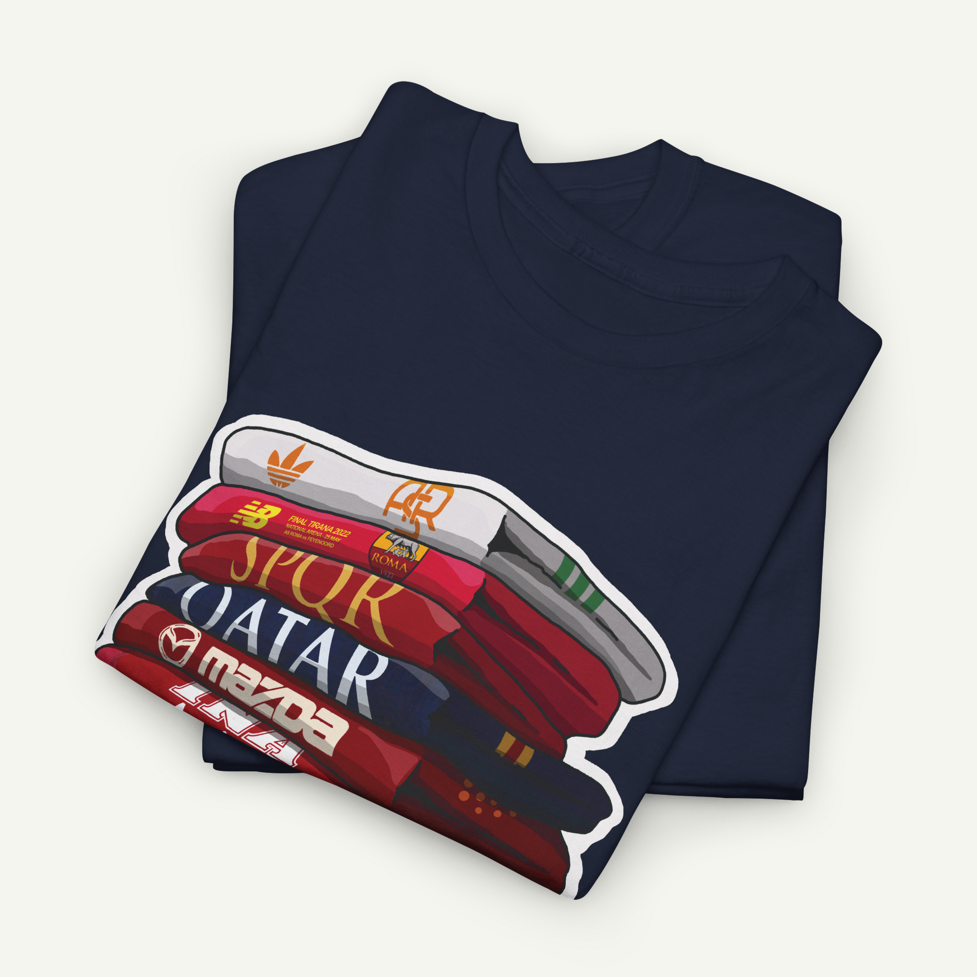 A navy blue t-shirt with a graphic design depicting a stack of books or magazines with the titles "SPUR", "QATAR", "maZDA", and "adidas" printed on them.