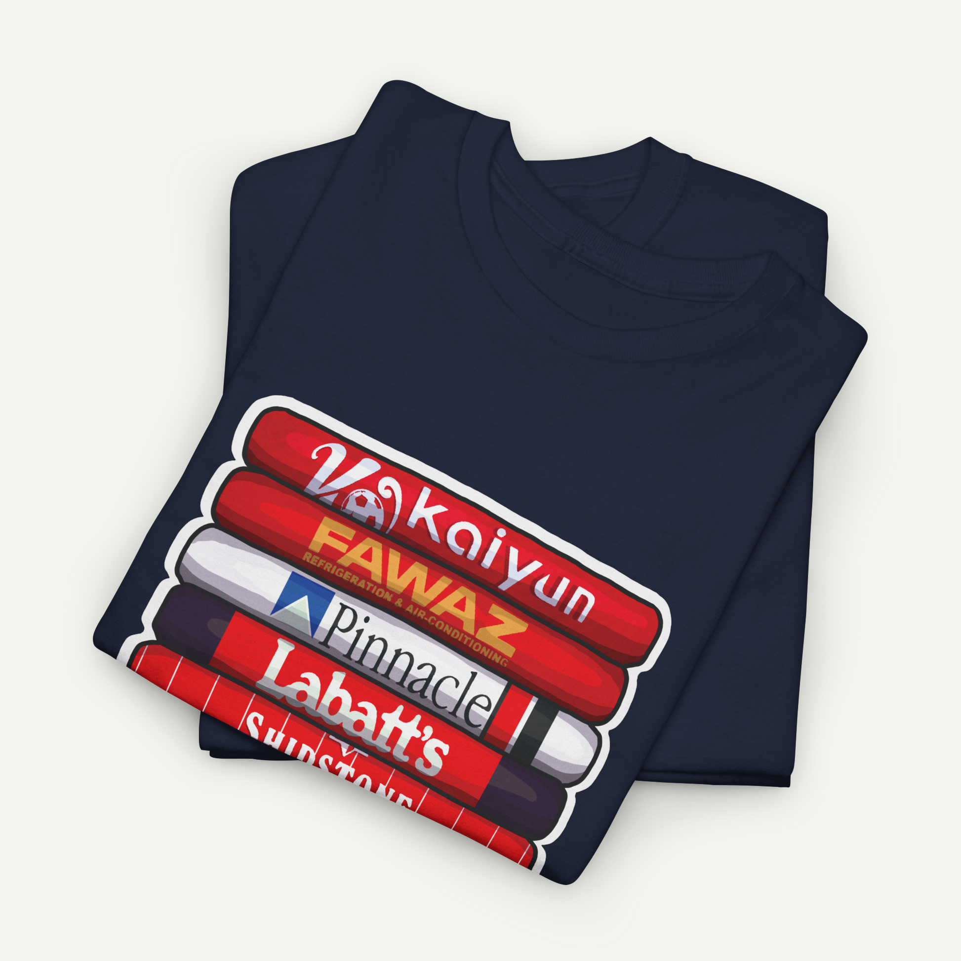 A navy blue t-shirt with a graphic design featuring a stack of red and white books with the text "Vakkyun", "FAWAZ", "Pinnacle", "Labatt's", and "Sunset" printed on it.