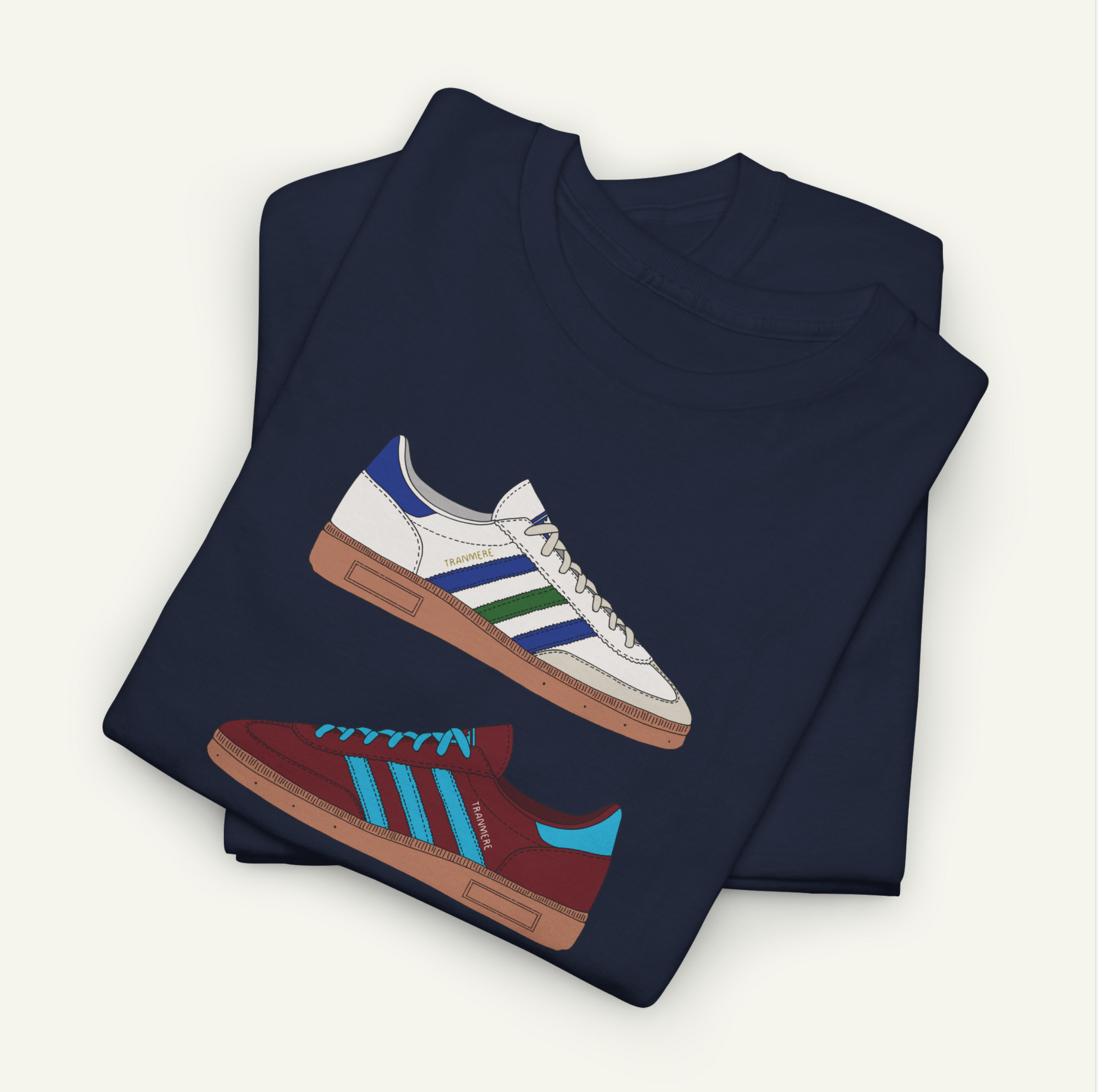 A dark blue t-shirt with a graphic design of two different colored Adidas sneakers printed on it.