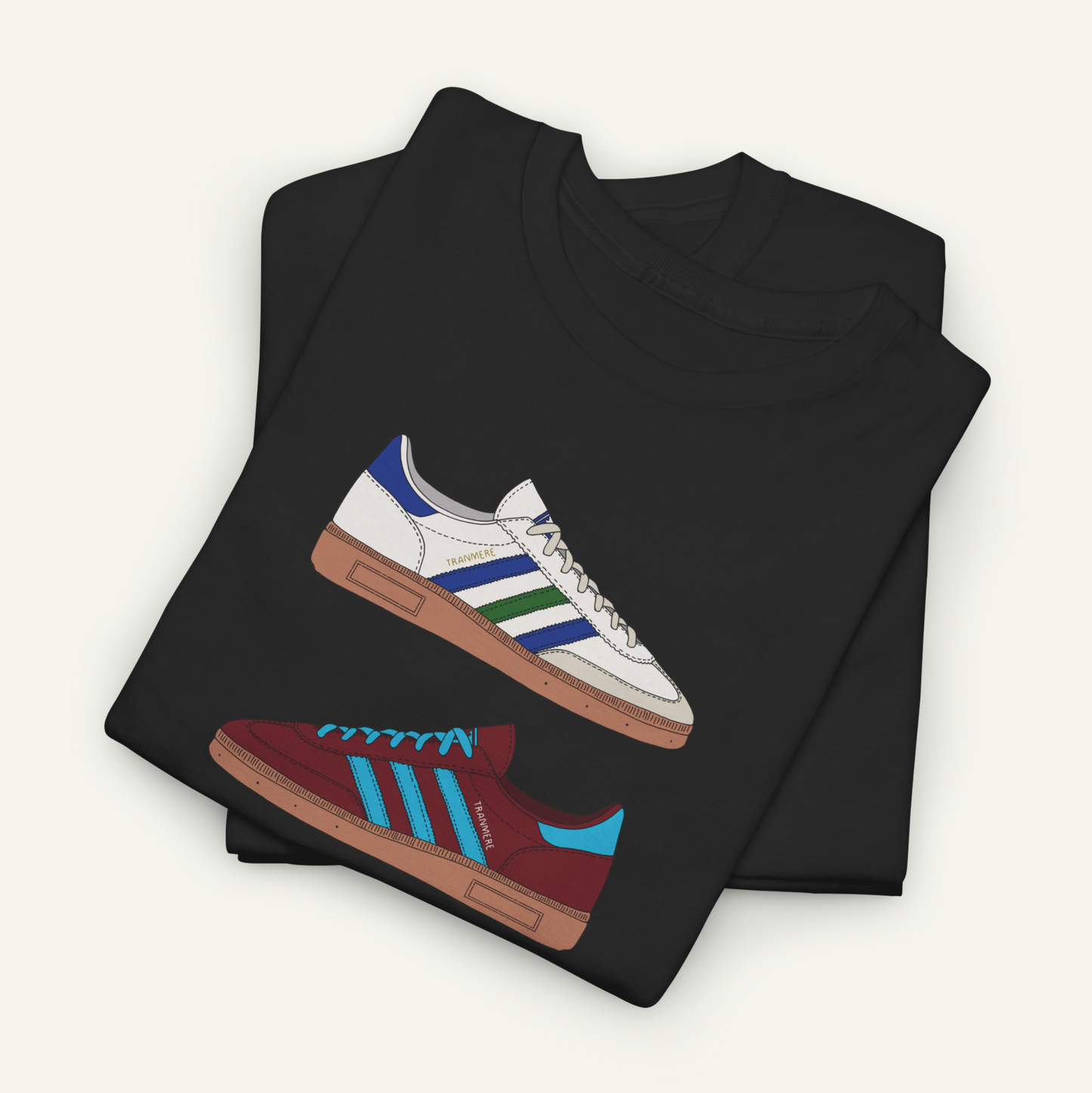 A black t-shirt with a graphic design of two Adidas sneakers, one white and one maroon, printed on it.