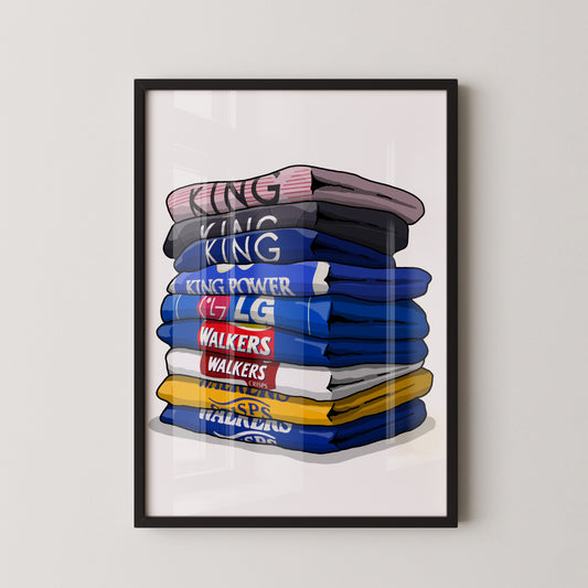 A framed illustration of a stack of folded shirts with various text printed on them.