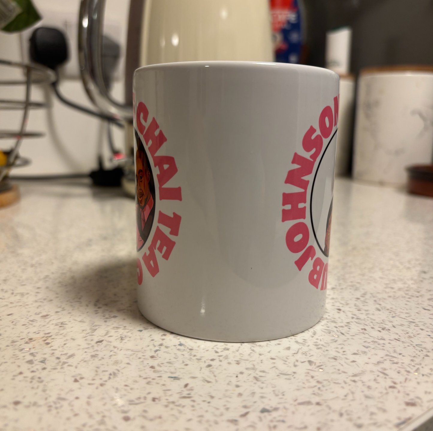 A white mug with a red circular logo featuring a person's face.