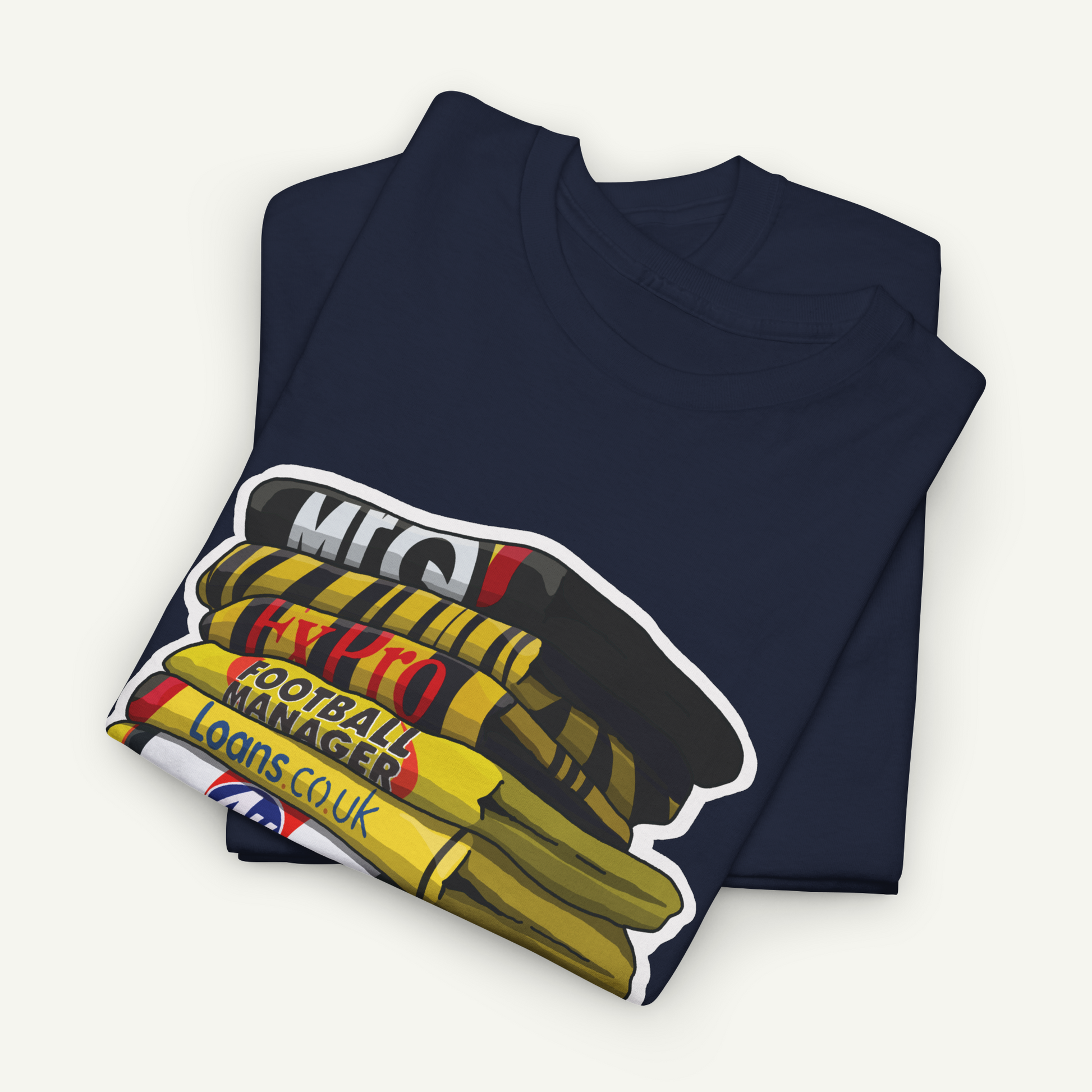 A navy blue t-shirt with a graphic design depicting a stack of books or magazines with the text "MEC" and "FOOTBALL MANAGER LOANS COU".