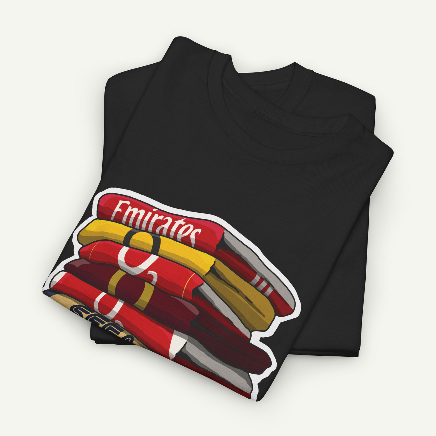 A black t-shirt with a graphic design depicting a stack of colorful books or magazines.