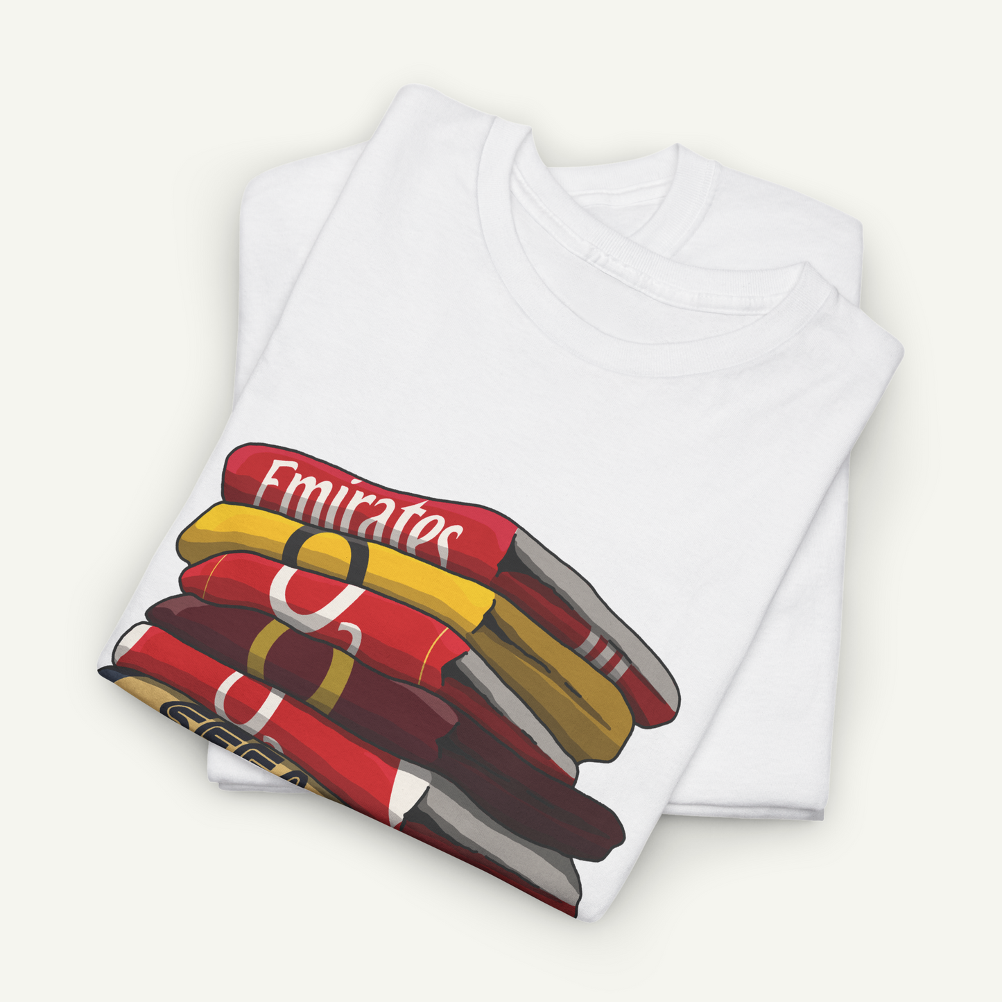 A white t-shirt with a graphic design depicting a stack of colorful books or magazines.