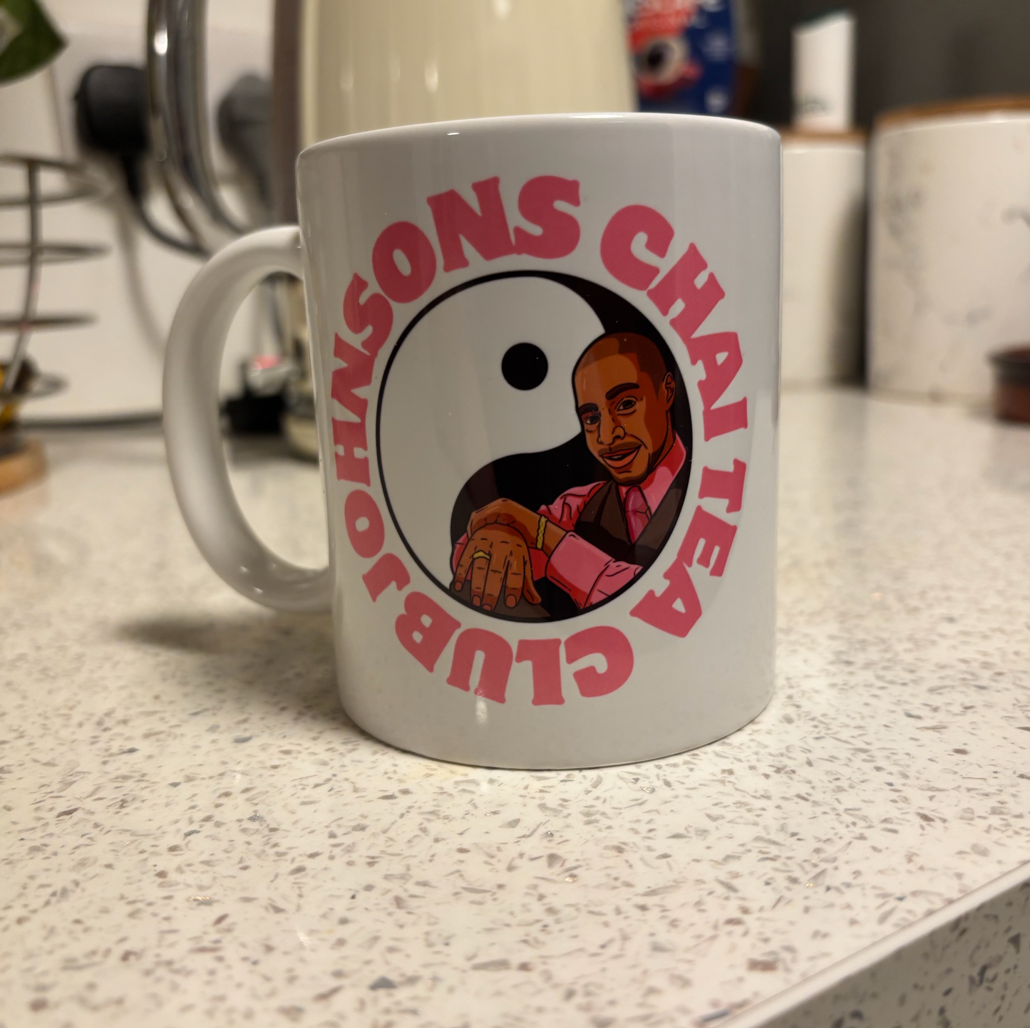 A white mug with a graphic design featuring a man in a pink shirt and a yin and yang symbol.