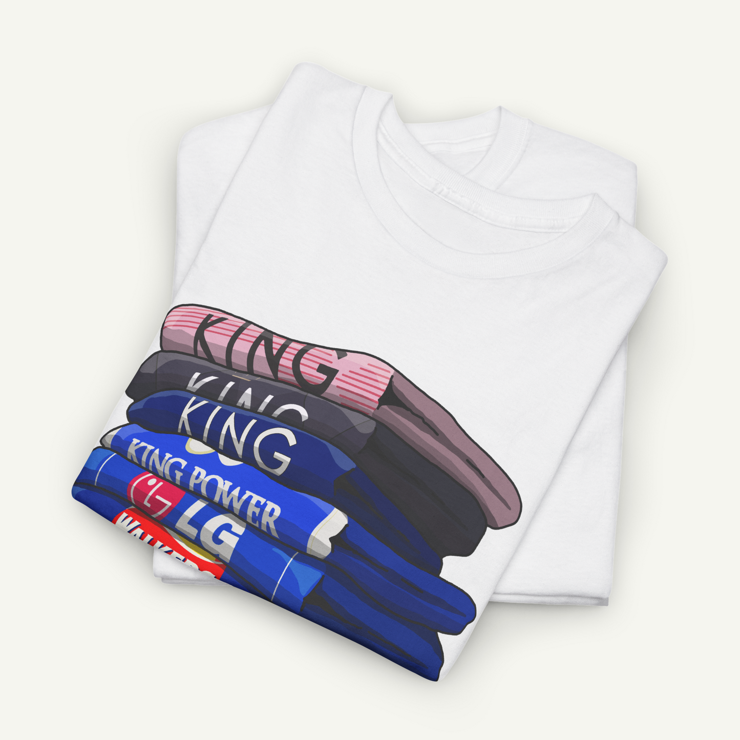 A white t-shirt with a graphic design depicting a stack of books or magazines with the word "KING" printed on them in various colors.