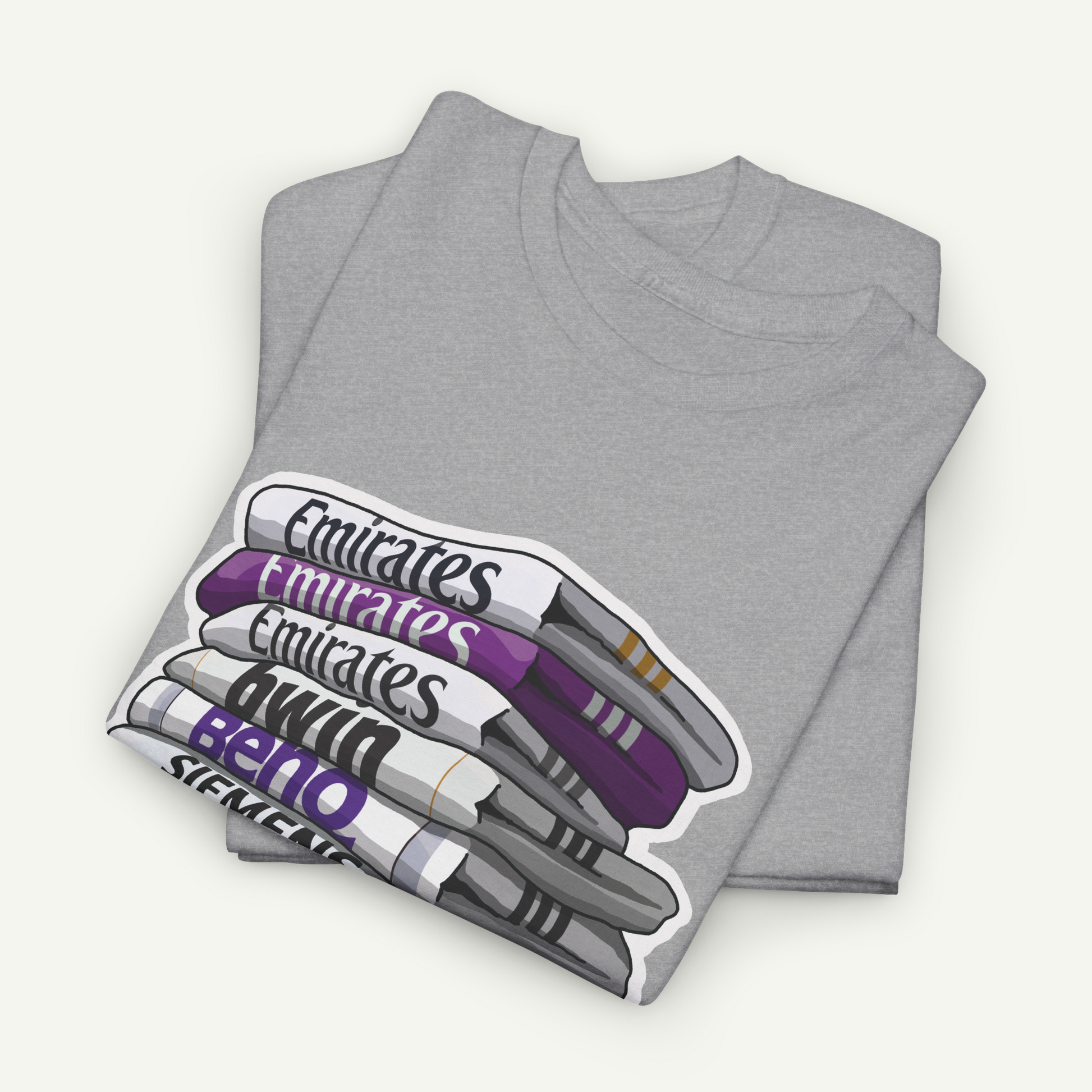 A gray t-shirt with a graphic design depicting a stack of books or magazines with the text "Emirates" written on them.