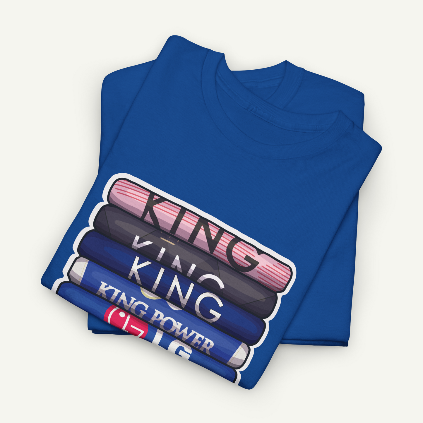 A blue t-shirt with the text "KING" printed on it, along with a graphic design of a stack of books or magazines.