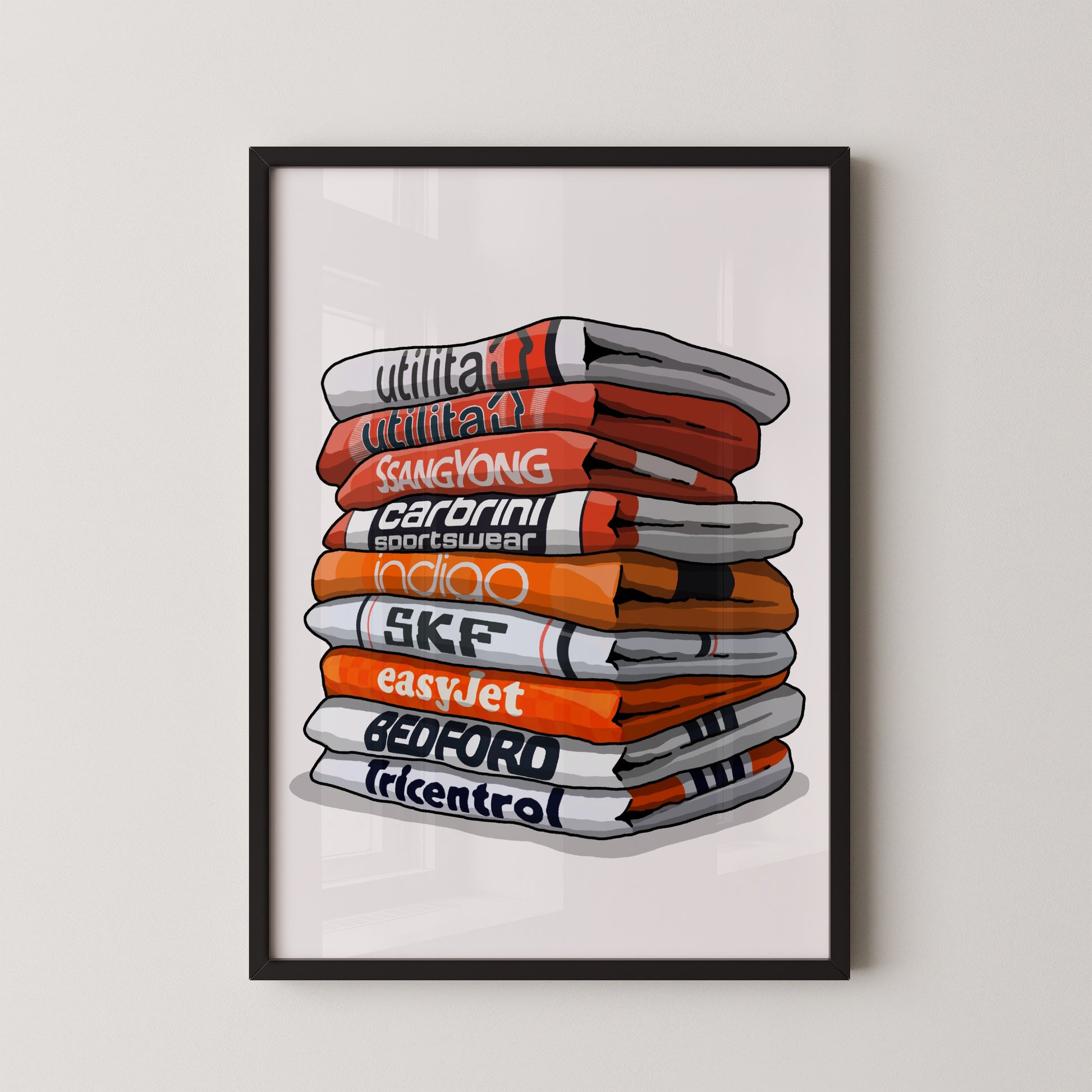 A framed illustration of a stack of colorful towels with various text printed on them, including "utilitat", "Sangyong", "CARBINI", "indio", "SKF", "easyJet", "BEDFORD", and "tricentro".