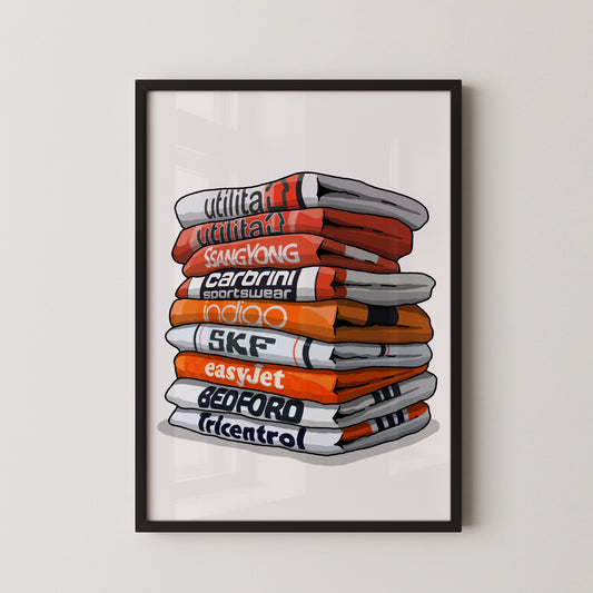 A framed illustration of a stack of colorful towels with various text printed on them, including "utilitat", "Sangyong", "CARBINI", "indio", "SKF", "easyJet", "BEDFORD", and "tricentro".